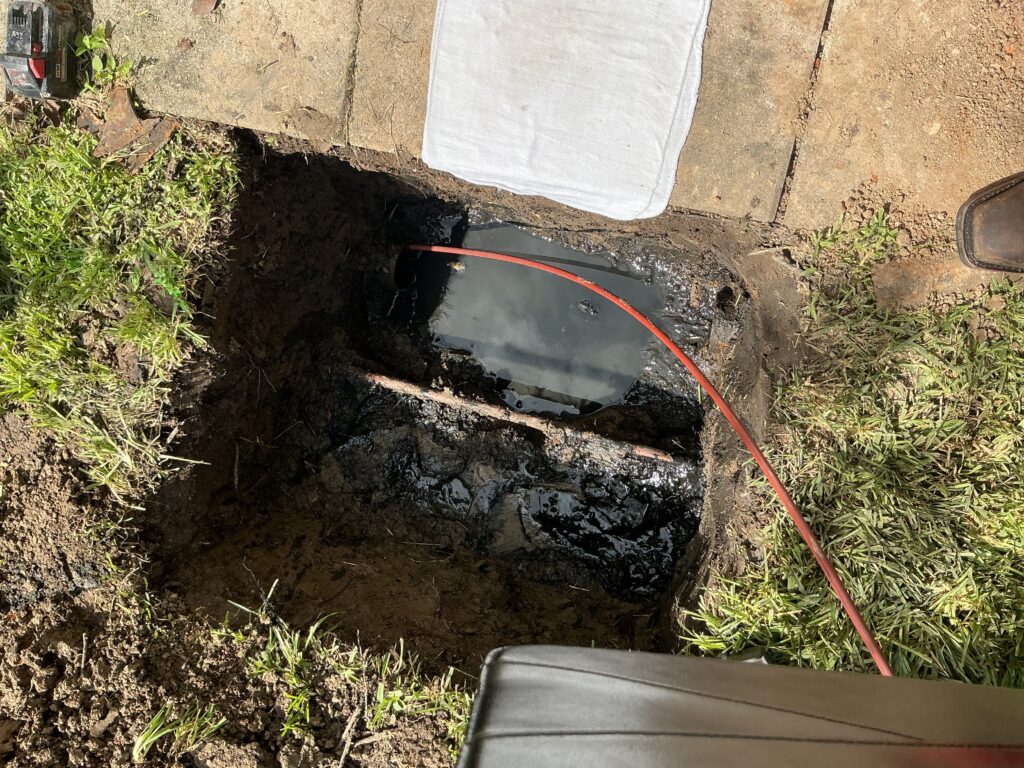 Open sewer access excavation beside a walkway during ADR diagnostic work in Thibodaux